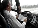 Bus driver reads manual while driving.